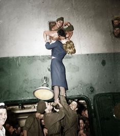 a woman is lifted in the air by two men while others look on from below