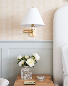 a small table with flowers on it next to a lamp