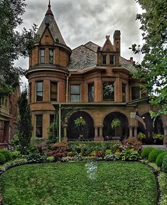 an old victorian house is surrounded by lush green grass