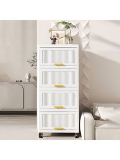 a white cabinet with yellow knobs in a modern living room, next to a couch