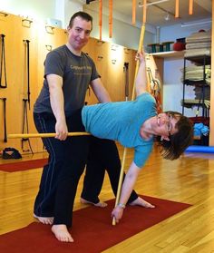 a man and woman doing exercises in a gym with yoga mats on the floor behind them