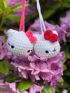 two crocheted hello kitty ornaments hanging from purple flowers