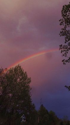 a rainbow appears in the sky above some trees