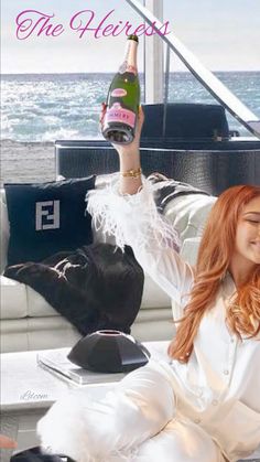 a woman sitting on top of a couch next to a bottle of wine in her hand