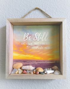 a wooden frame with seashells in it and the words, be still and know that i am god