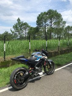 a motorcycle is parked on the side of the road in front of some tall grass