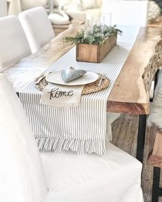 a wooden table topped with a white plate and vase filled with greenery on top of it