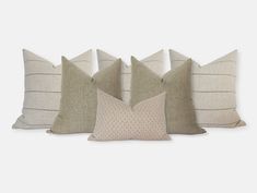 five pillows lined up against each other on a white background, one in grey and the other in beige