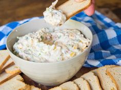 a person dipping some kind of food into a bowl with crackers on the side