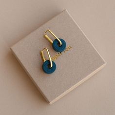 two pairs of blue earrings sitting on top of a white box next to each other