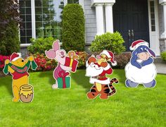 winnie the pooh and friends yard decorations in front of a house with flowers on the lawn