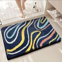 a bathroom rug that is on the floor in front of a bathtub with a person standing next to it