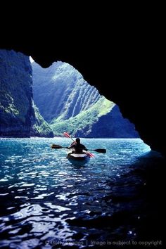 a person in a kayak paddling through a cave