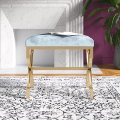 a white and gold bench sitting on top of a rug next to a plant in a living room