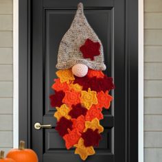 a door decorated with an orange and red knitted hat, stars and pumpkins