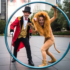 two people dressed in costumes are posing for a photo inside a hoop with one person wearing a lion costume and the other holding a microphone