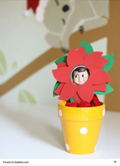 a doll in a flower pot with a red flower on it's head and eyes