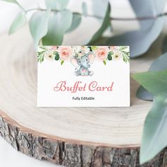 a business card with an elephant and flowers on it sitting next to a tree stump