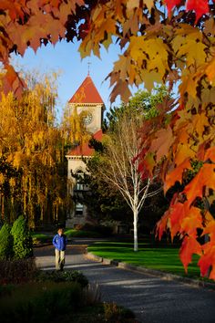 a man walking down a path in front of a building with a clock tower on top