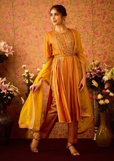 Step into refined elegance with the yellow mustard hand-embroidered pleated silk brocade kurta, perfectly paired with brocade pants. This exquisite ensemble features intricate hand embroidery that adds depth to the luxurious fabric, while the pleated design offers a graceful silhouette. An embroidered belt accentuates the waist, and the matching dupatta completes the look, making it an ideal choice for festive occasions and celebrations. Gold Cotton Silk Palazzo Set With Dabka Work, Yellow Anarkali Cotton Silk Kurta, Yellow Raw Silk Palazzo Set With Dabka Work, Yellow Embroidered Silk Kurta, Transitional Gold Silk Palazzo Set, Yellow Raw Silk Kurta With Traditional Drape, Elegant Yellow Palazzo Set With Straight Kurta, Gold Silk Palazzo Set For Transitional Season, Gold Silk Palazzo Set With Straight Kurta