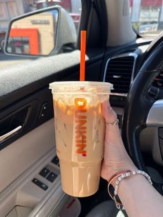 a person holding a cup in their hand while sitting in the driver's seat of a car