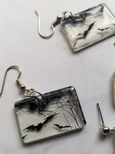 three pieces of glass sitting on top of a white table next to silver ear wires