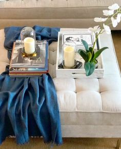 a white couch sitting next to a table with two candles and flowers on top of it