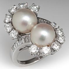 This captivating by-pass style ring is centered with two (2), post set, cultured saltwater pearls. The pearls are each bordered with six (6), prong set, round brilliant cut diamonds. The top face of the shank is accented with six (6), channel set, baguette cut diamonds on each side. The ring measures 24.1mm at the top, rises 10.0mm above the finger, tapering to 1.9mm wide and 1.6mm thick at the base of the shank. This ring is currently a size 6. The pearls in this ring appear to be from a strand Luxury Victorian Pearl Ring For Formal Events, Luxury Elegant Pearl Ring With Rose Cut Diamonds, Modern Luxury White Gold Pearl Ring, Pearl Rings Vintage Sales, Luxury Victorian Pearl Ring For Formal Occasions, Luxury Oval Pearl Ring For Wedding, Luxury Pearl Ring With Vvs Clarity As Gift, Luxury Unique Pearl Rings, Luxury Timeless Pearl Ring For Anniversary