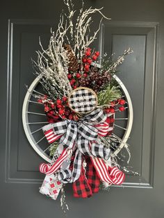 a wreath on the front door with red, white and black ribbons hanging from it