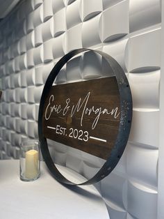 a wooden sign sitting on top of a white table next to a candle and vase