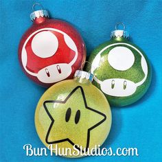 three christmas ornaments are sitting on a blue background with the words, super mario bros