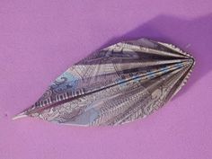 an origami feather on a purple background