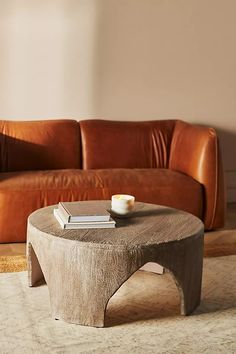 a living room with a couch, coffee table and books on the end tables in front of it