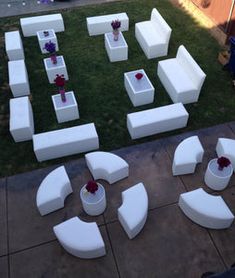 white couches and tables are arranged on the grass in front of a building with red roses