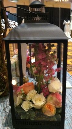 a black lantern with flowers in it on a table