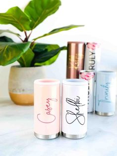 three personalized tumbles sitting on top of a counter next to a potted plant