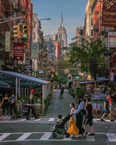 people are crossing the street at an intersection in new york city, with tall buildings behind them