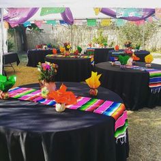 tables covered with black tablecloths and colorful decorations in an outdoor setting for a party