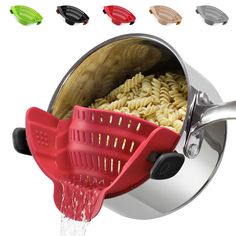 a red colander with pasta in it being filled with water from the faucet