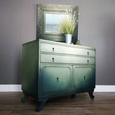 a green dresser with a mirror and potted plant on top