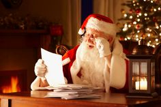 a man dressed as santa claus sitting at a desk with papers in front of him