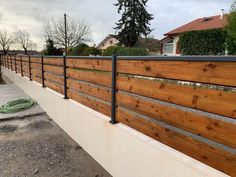 a wooden fence next to a street with houses in the background