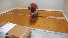 a man is working on the floor in an empty room with cardboard boxes around him