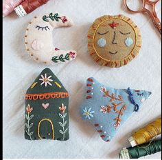 four different handmade items sitting on top of a white cloth covered table next to scissors and thread