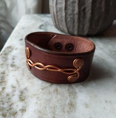 Rugged Men's Leather Bracelet. One of a kind. Made from full grain hand dyed veg tan leather with hammered copper design on front. MADE IN USA. Double snap closure on back. 8" long x 1.5 " wide. Perfect guy gift for any occasion. Can be personalized with initials. Brown Handmade Cuff Bracelets, Handmade Brown Cuff Bracelets, Handmade Distressed Brown Adjustable Bracelet, Artisan Copper Cuff Bracelet Adjustable, Handmade Adjustable Brown Cuff Bracelet, Artisan Copper Cuff Bracelet With Adjustable Fit, Adjustable Copper Artisan Cuff Bracelet, Adjustable Artisan Copper Cuff Bracelet, Artisan Adjustable Copper Cuff Bracelet