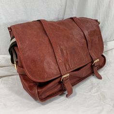 "Measurements are 17\" wide, 11\"5 high, 8\" deep with one 44\" shoulder strap with a 18\" drop. On the interior there is one large main compartment, back zipper pocket, cell phone slot and two front buckle closures. Bag is made of pebbled leather with silver/gold tone hardware, strong leather with no tears and bag was well cared for. The color of this bag is between currant red and light brown. This leather messenger bag is spacious with great detail and bag can be used crossbody. ------------- Leather Saddle Shoulder Bag With Large Capacity, Travel Satchel Saddle Bag With Adjustable Strap, Travel Saddle Bag Satchel With Adjustable Strap, Large Capacity Leather Flap Satchel, Large Capacity Leather Satchel With Flap, Burgundy Travel Satchel Shoulder Bag, Burgundy Satchel Shoulder Bag For Travel, Travel Burgundy Satchel Shoulder Bag, Burgundy Travel Bag With Adjustable Strap