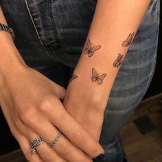 a woman's arm with butterfly tattoos on her left wrist and the other hand