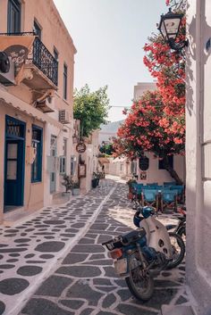 a motorcycle parked on the side of a street next to a building with red flowers