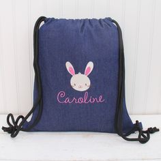 a blue drawsack bag with a bunny face on the front and name caroline in pink