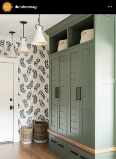 a room with green cupboards and wallpaper on the walls next to a wooden floor